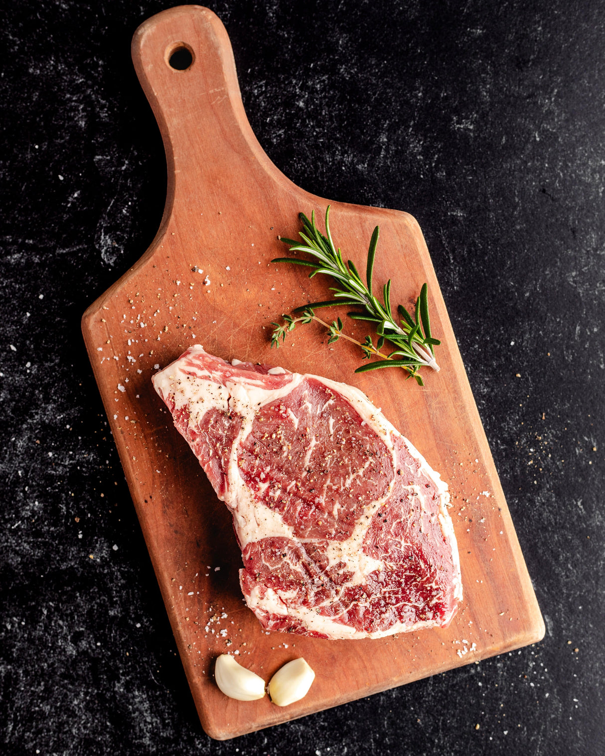 a seasoned ribeye steak on a cutting board