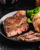 a sliced ribeye steak with vegetables and potato